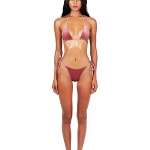 May include: A woman wearing a dusty rose velvet bikini top and matching bikini bottom. The bikini top is a triangle style with thin straps. The bikini bottom is a tie-side style.
