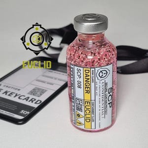 May include: A clear glass vial filled with pink liquid and small particles, topped with a silver cap. The label reads SCP SECURE CONTAIN PROTECT, DANGER, EUCLID, and SCP-008. Beside it lies a black lanyard and a rectangular ID card holder.