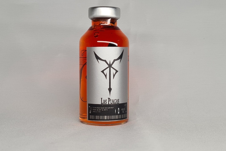 May include: A small glass bottle with a silver cap, filled with a bright orange liquid. A silver label displays a black emblem and the words "Las Plagas". The bottle has a barcode and other text.