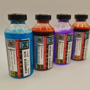 Könnte beinhalten: Vier Glasflaschen mit schwarzen Deckeln und farbigen Flüssigkeiten. Die Flaschen haben Etiketten mit dem Text "MONARCH", "Biological Hazards" und "BLOODSAMPLE". Die Flüssigkeiten sind blau, rot, lila und orange.