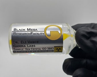 May include: A clear glass vial with yellow liquid inside, labeled "BLACK MESA RESEARCH FACILITY." The label also includes "Dr. Eli Vance, GAMMA LABS, SAMPLE: Xen Crystal GG-3883." The vial is held by a gloved hand.