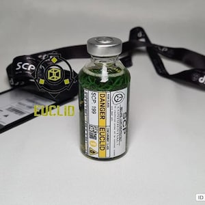Pode incluir: Um frasco de vidro transparente preenchido com líquido verde, com uma tampa prateada e um rótulo branco com o texto DANGER, EUCLID, SCP-199 e vários símbolos de aviso. O frasco está posicionado à frente de um cordão preto com a marca SCP.