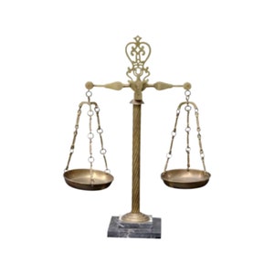 May include: A vintage brass balance scale with two circular pans suspended by chains. The scale has a decorative top and sits on a black and gray marble base. The central support is a twisted column.