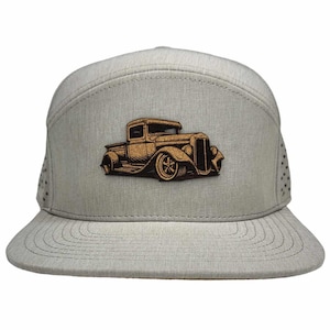May include: A gray and brown baseball cap with a vintage truck design. The truck is made of cork and is a brown color. The cap is made of a breathable material and has a mesh back.