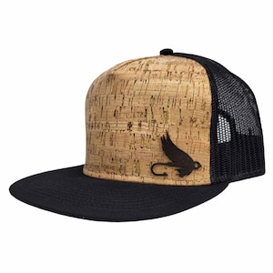 May include: A brown cork and black mesh trucker hat with a black fly fishing lure design on the front.