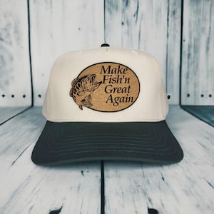May include: A white and black baseball cap with a cork patch that says "Make Fish'n Great Again" and a brown bass fish graphic.