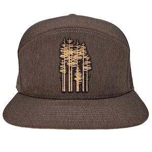 Puede incluir: Una gorra de béisbol marrón y negra con un diseño bordado en oro y negro de un grupo de árboles.