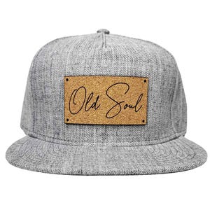 May include: A gray and black baseball cap with a cork patch that says "Old Soul" in cursive.