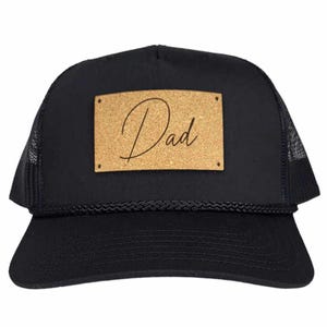 May include: Black trucker hat with a cork patch that says "Dad" in cursive.