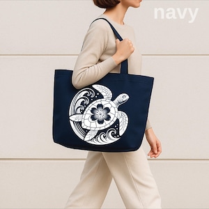 May include: Navy blue tote bag featuring a white turtle design with a flower on its shell. The bag has a rectangular shape with sturdy handles. The word "navy" is printed in the upper right corner.