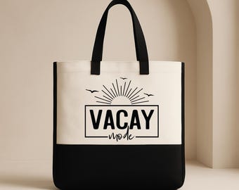 Könnte beinhalten: Eine zweifarbige Tragetasche mit schwarzem Boden und cremefarbenem Oberteil. Die Tasche hat schwarze Griffe und eine Grafik mit der Aufschrift "VACAY mode" mit einem Sonnenaufgangsdesign und Vögeln. Die Worte "CUSTOM TEE HAUS" sind unten links aufgedruckt.