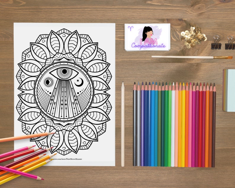 May include: A black and white colouring page featuring a mandala with an eye in the centre. The mandala is surrounded by a circle of leaves. The page is titled "New Moon Mandala".