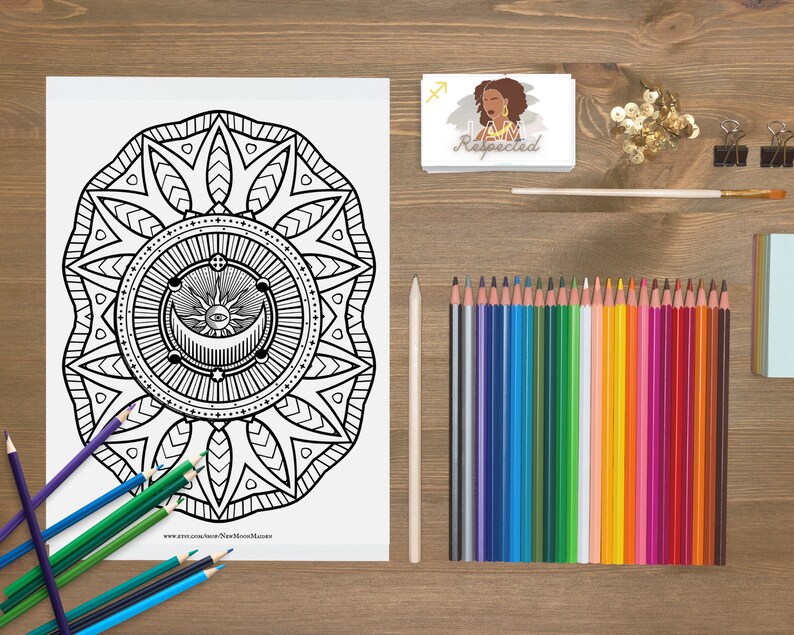 May include: A black and white colouring page featuring a mandala design with a sun, moon, and eye in the centre. The mandala is surrounded by a border of leaves and flowers. The page is titled "New Moon Magic".