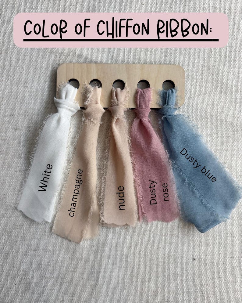 May include: A wooden display board with five chiffon ribbon samples in white, champagne, nude, dusty rose, and dusty blue. Each ribbon is labeled with its color name. The text "COLOR OF CHIFFON RIBBON:" is at the top.
