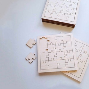 Puede incluir: Dos rompecabezas de madera sin terminar, uno con una pieza faltante. Los rompecabezas son de madera marrón claro y tienen un fondo blanco. Los rompecabezas son cuadrados y tienen un diseño simple.
