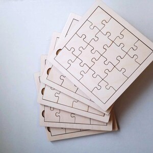 May include: A stack of five unfinished wooden jigsaw puzzles, each with a different number of pieces. The puzzles are all the same size and shape, and they are all made of light-colored wood.