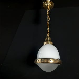 Op de afbeelding: Een messing hanglamp met een witte, gematteerde glazen kap. De lamp heeft een ketting en een ronde plafondbevestiging.