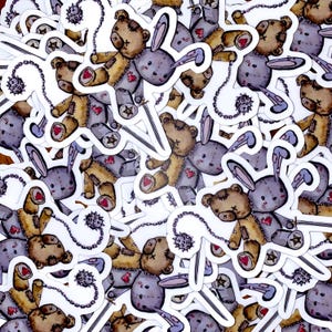 Può includere: Un mucchio di adesivi colorati con un orsacchiotto di cartone animato con orecchie di coniglio che tiene una catena con punte. L'orsacchiotto è cucito con punti visibili e ha un cuore sul petto. Gli adesivi sono su uno sfondo bianco.