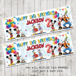 May include: Two rectangular birthday banners featuring Disney characters. The banners read "Happy 2nd Birthday Jackson" with a large number "2". Each banner features Mickey and Minnie Mouse, Donald and Daisy Duck, and Goofy. Each banner is 90cm x 30cm.