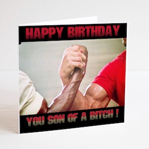 May include: Birthday card with the text "HAPPY BIRTHDAY" in red. The card features a still from a movie with two men arm wrestling. The text "YOU SON OF A BITCH!" is also displayed.