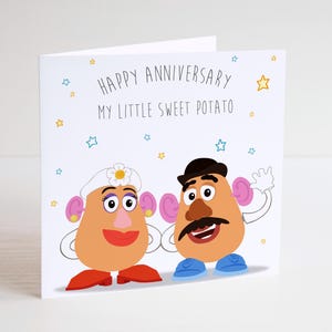May include: A white anniversary card with the message "Happy Anniversary My Little Sweet Potato." The card shows cartoon potato characters with pink ears, red lips, and blue shoes. Stars are scattered around the card.