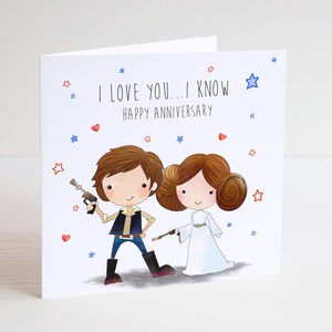 May include: A white greeting card featuring a cartoon illustration of two characters. The text reads I LOVE YOU... I KNOW HAPPY ANNIVERSARY. The male character wears a dark vest and blue trousers, while the female character wears a white dress.