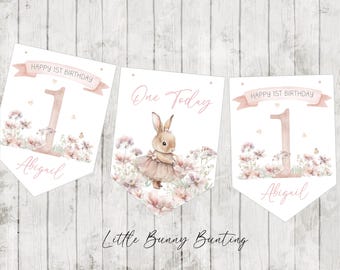 Op de afbeelding: Een verjaardagsslinger bestaande uit drie vlaggetjes met aquarelillustraties van een konijntje in een tutu, roze bloemen en de tekst Happy 1st Birthday, One Today en de naam Abigail in een zachtroze en wit kleurenpalet.