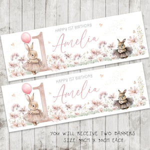 May include: Two banners with a floral design and the text "Happy 1st Birthday Amelia." Each banner features a bunny wearing a tutu and holding a pink balloon. The banners are 35.4 inches by 11.8 inches.