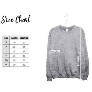 a gray sweatshirt hanging on a hanger, with a size chart and measurements displayed next to it.