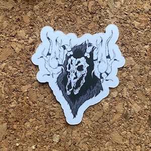 Könnte beinhalten: Ein schwarz-weißer Aufkleber mit einem Schädel mit Hörnern und einer pelzigen Mähne. Der Schädel ist von Flammen umgeben.
