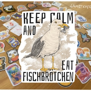 Può includere: Un adesivo con un gabbiano che tiene un pesce nel becco, con il testo "KEEP CALM AND EAT FISCHBROTCHEN" in lettere nere. L'adesivo è circondato da vari adesivi colorati su una superficie di legno.