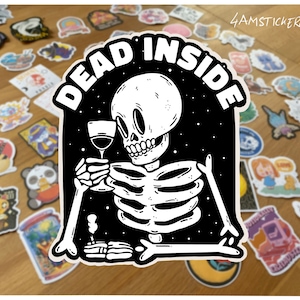 Op de afbeelding: Zwart-witte sticker met een skelet dat een glas wijn vasthoudt met de tekst "DEAD INSIDE" in een witte cirkel.