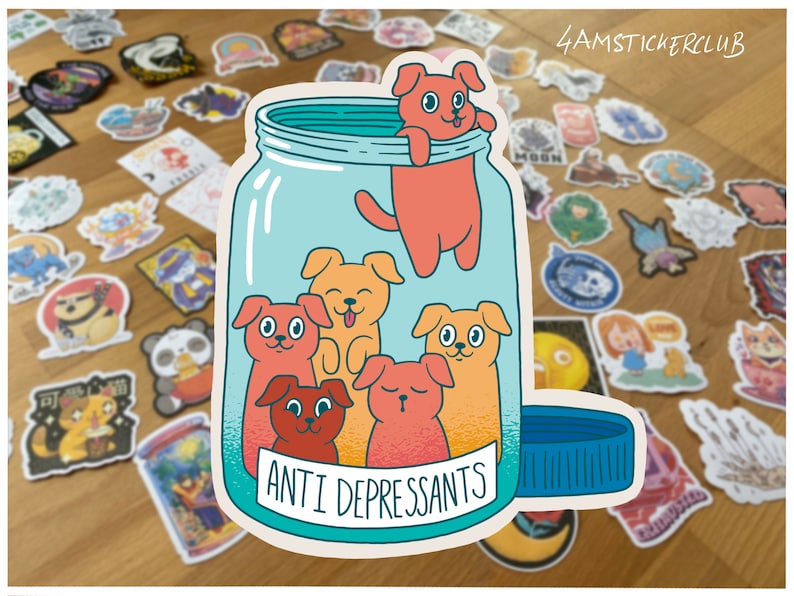 May include: A sticker of a glass jar with a blue lid and the text "Anti Depressants" on the label. Inside the jar are five cartoon dogs in various colors, with one dog peeking out of the top of the jar.