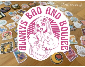 May include: A white sticker with a pink outline and text that reads "ALWAYS BAD AND BOUJEE." The sticker features a cartoon illustration of a woman with long hair, a finger to her lips, and a fur-trimmed jacket. Other stickers are in the background.