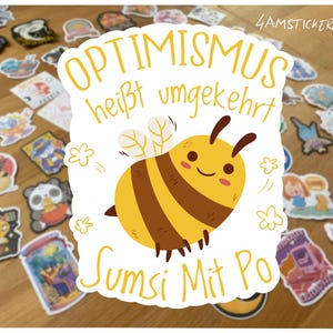 May include: A sticker featuring a cartoon bee with brown stripes and a smiling face. The sticker has the text "OPTIMISMUS heißt umgekehrt Sumsi Mit Po" in yellow. Other stickers are scattered around the main sticker.