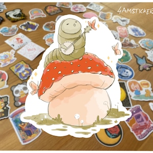 Caterpillar sitting on top of a mushroom and playing banjo sticker green caterpillar sticker retro vintage artwork sticker 80s style sticker