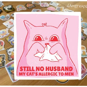 May include: A pink square sticker featuring a cartoon cat holding a tissue. The cat has red eyes and is surrounded by a white border. The text reads "STILL NO HUSBAND MY CAT'S ALLERGIC TO MEN". Other stickers are scattered around.