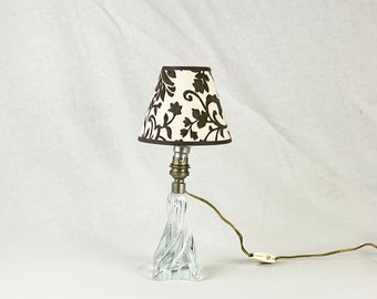 May include: A small table lamp with a clear crystal base and a brown and white patterned lampshade.