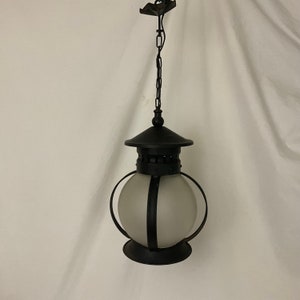 Pode incluir: Luminária pendente de metal preto com um globo de vidro fosco e uma corrente pendurada no teto.