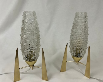 May include: A pair of vintage mid-century modern table lamps with brass rocket-shaped bases and clear textured glass shades.