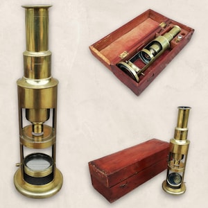 May include: Two antique brass microscopes with wooden storage boxes. The microscopes have a brass body with a round base and a long, thin tube. The boxes are made of dark wood with a hinged lid.