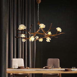 May include: A decorative chandelier with a branch-like design, featuring multiple glowing flower-shaped lights. The fixture is suspended from the ceiling by a chain and is made of brown metal. The lights are a warm, inviting colour.