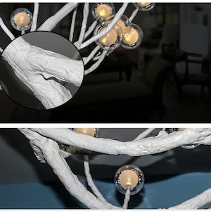 May include: White, twig-like branches form a unique chandelier with clear glass globes containing warm white lights. The branches are textured to resemble natural wood.