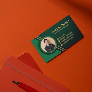 Può includere: Un biglietto da visita verde e dorato con la foto di una persona in abito. Il testo sul biglietto recita "Harper Russo, Assistente Amministrativo, 123-456-7890, hello@reallygreatsite.com, www.reallygreatsite.com, 123 Anywhere St, Any City".