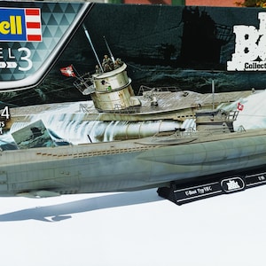 May include: A 1:144 scale model of a U-Boat Type VIIC submarine, with 87 parts. The box art features the Revell logo and the text "Das Boot Collector's Edition". The model is grey and has detailed features, including a conning tower and deck details.