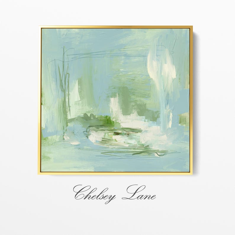May include: Abstract art print in a gold frame. The artwork features a blend of light blue, green, and white brushstrokes, creating a serene and airy composition. The painting is signed "Chelsey Lane" in cursive script at the bottom.
