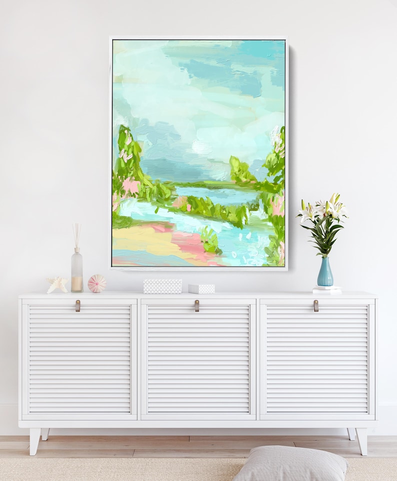May include: Abstract landscape painting with a blue, green, and pink color scheme. The painting depicts a river flowing through a lush green landscape with a cloudy sky above.