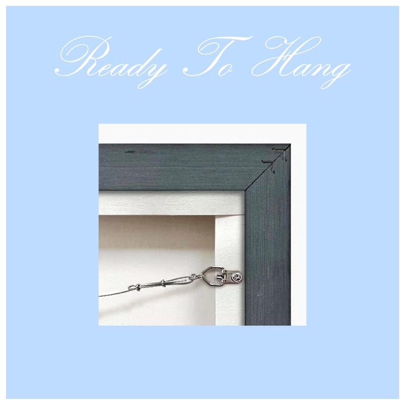 May include: Close-up of a dark gray wood picture frame with a metal hanging wire attached to the back. The frame is ready to hang on a wall.