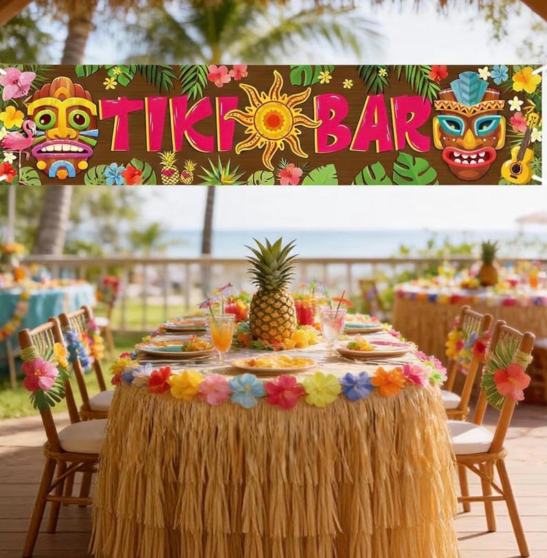 May include: A festive Tiki Bar banner with colorful floral and tribal mask designs. A table is set with a pineapple centerpiece, drinks, and plates. The table is decorated with a raffia skirt and flower garland, creating a tropical theme.