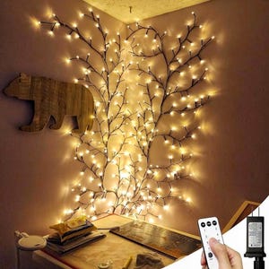 Puede incluir: Un conjunto de luces de hadas blancas cálidas con forma de ramas con un mando a distancia. Las luces están colgadas en una pared en una esquina de una habitación.